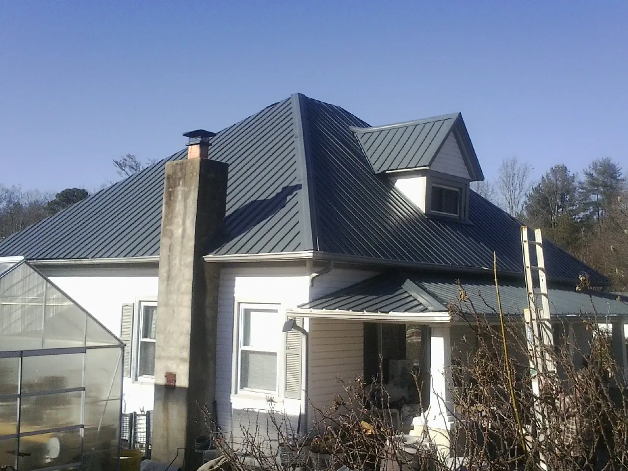 Dark blue standing seam metal roof on a white farmhouse with dormer — Slate & Tile Roof Repair by Roofing Brothers in Green Bay