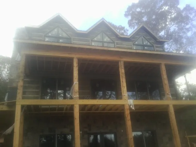Dormers and porch framing on a large log home under construction — Roof Coating work by our crew in Green Bay