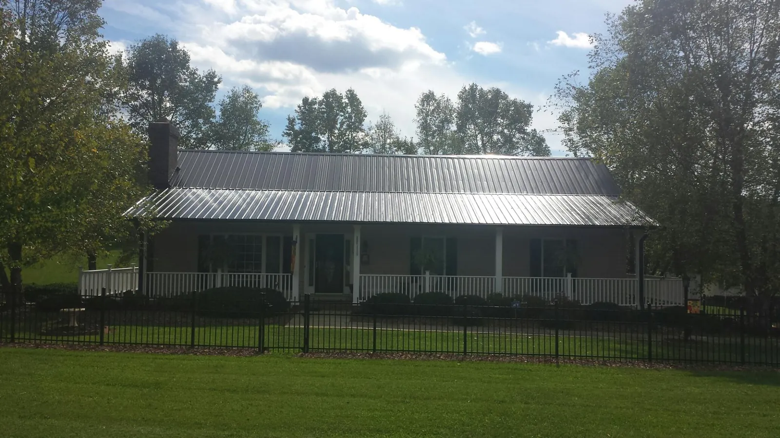 Gray metal roof on a brick ranch with a full width front porch — Gutter Guard Installation work by our crew in Green Bay